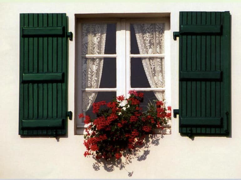 Зеленые ставни в сочетании с цветами на окнах