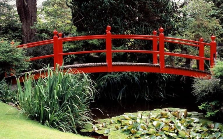 Яркий красный садовый мостик из дерева фото