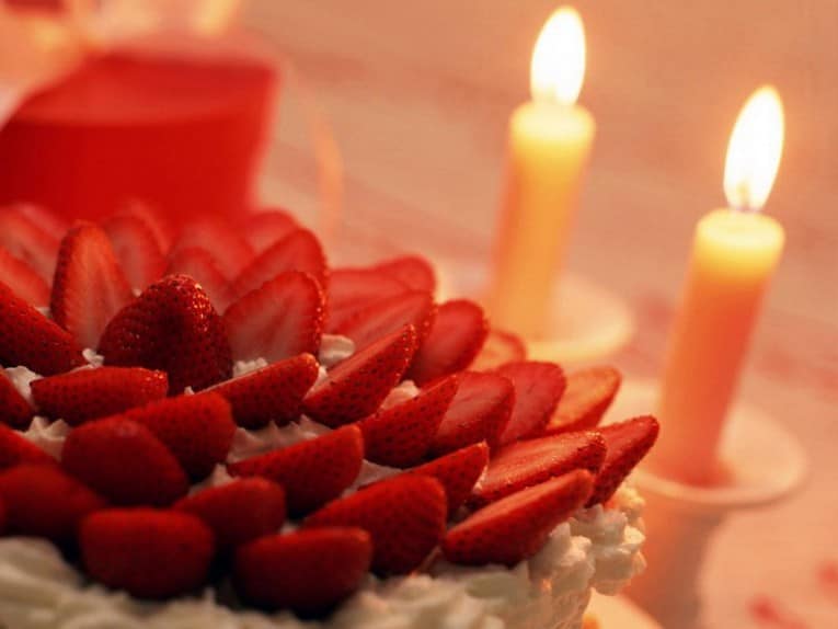 Свечи на праздничном столе и клубника со сливками на десерт