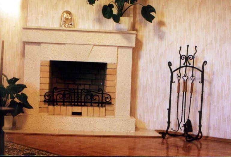 Кованая каминная решетка и набор для камина в интерьере гостиной