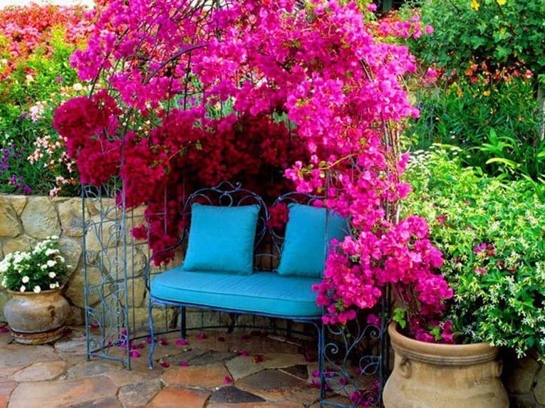 Металлическая арка с цветами в уголке отдыха в саду